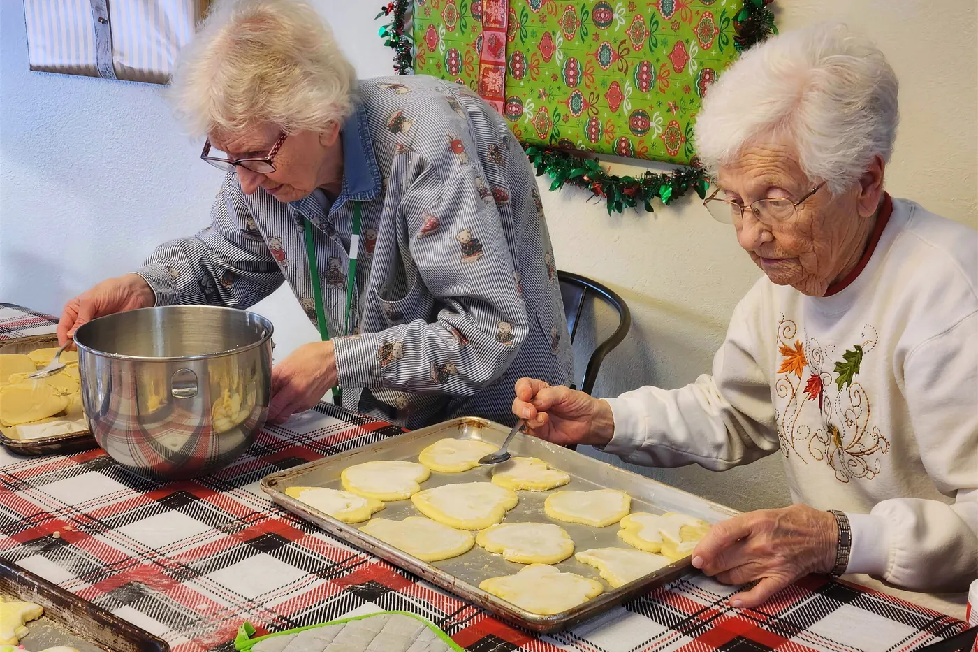 Residents rolling and cutting sugar cookies at a kitchen table at Aspen Leaf